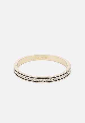 Bracelet jonc doré avec bande en émail noir et motif répété du logo Coach autour du bord extérieur.