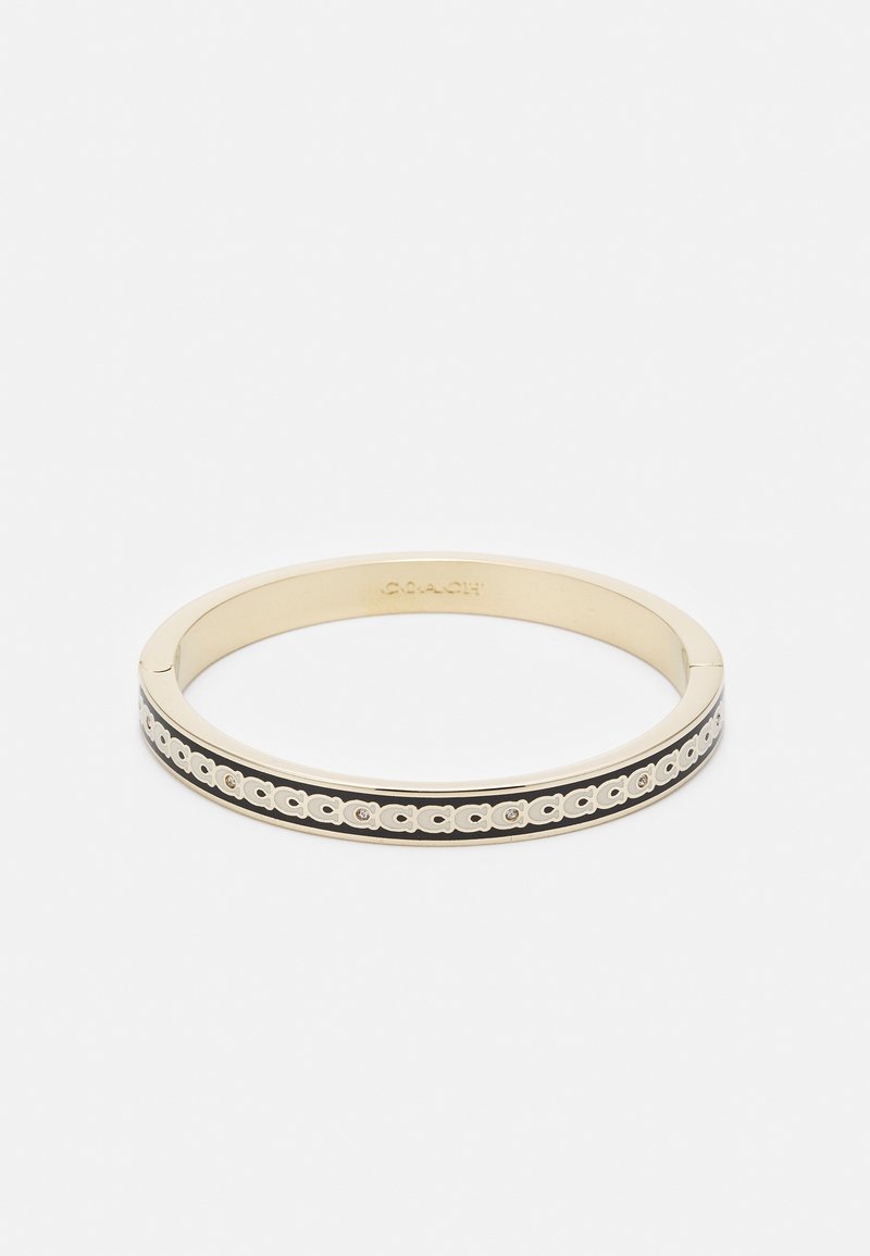 Bracelet jonc doré avec bande en émail noir et motif répété du logo Coach autour du bord extérieur.