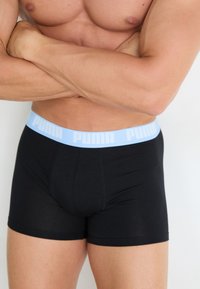 Boxeri negri din material elastic, cu un waistband de culoare albastră deschisă pe care este inscripționat textul "PUMA". Materialul pare neted și se adaptează perfect conturului corpului.