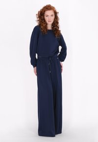 Marineblauwe twee-delige outfit met een lange mouwtop en wijde broekspijpen, gemaakt van zachte stof met een elastische tailleband en koord.