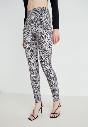 Leggings taille haute en tissu extensible, ornés d'un motif léopard noir et beige, conçus pour épouser la silhouette.