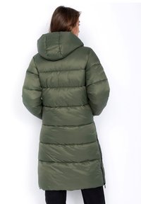 Olivgrüner Puffer-Mantel mit Kapuze, ausgestattet mit einem gesteppten Design und seitlichen Reißverschlüssen, bietet einen langen, gemütlichen Schnitt und einen glatten, glänzenden Stoff.