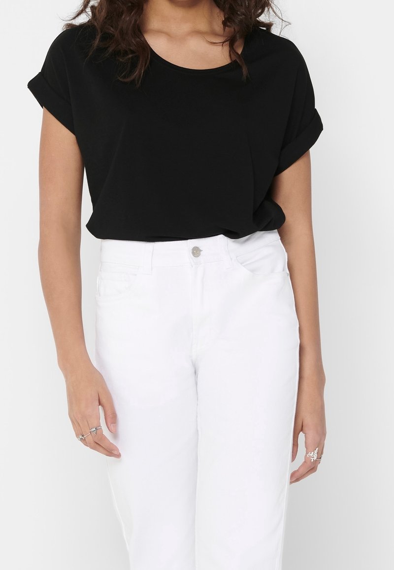 Haut noir à manches courtes avec un col rond, associé à un jean blanc taille haute. Texture lisse et coupe décontractée, design simple.