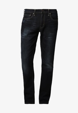 Dunkelblaue Jeans aus Denim mit ausgewaschenem Finish, gerade Passform, Five-Pocket-Design und kontrastierendem gelben Nähten entlang der Nähte.