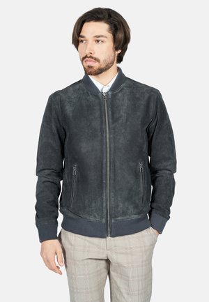 Chaqueta bomber para hombre en suave ante negro, con cierre completo, puños y dobladillo acanalados, y dos bolsillos laterales. Textura suave con un diseño minimalista.