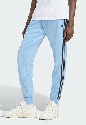 Pantaloni da corsa azzurro chiaro con strisce laterali nere e logo Adidas. Realizzati in tessuto liscio, presentano gambe affusolate e polsini a coste.