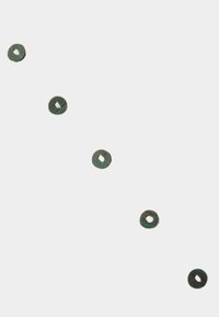 Perle circolari striate verde e nere con un foro centrale, di dimensioni variabili, disposte in formazione lineare su uno sfondo bianco.