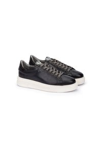 Zapatillas de cuero negras con cordones grises, punta redonda y suelas de goma blanca. Presenta un diseño minimalista y detalles cosidos.