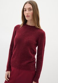 Bordeaux neulepaita pitkillä hihoilla, pyöreällä pääntiellä ja teksturoidulla pinnalla. Yhdistetty matching bordeaux-hameen kanssa.