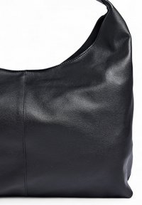 Sort læder skuldertaske med en glat tekstur, semi-struktureret form og en buet top. Har et minimalistisk design uden udsmykninger.