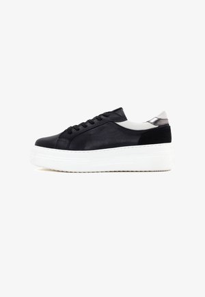 Baskets en cuir noir avec une semelle plateforme blanche, présentant une finition lisse, un système de laçage et un accent gris au talon.