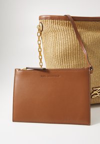 Woven straw tote bag with brown leather accents, featuring a chain strap and a matching brown leather pouch with embossed logo.