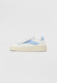 Fehér sneaker világoskék részletekkel, textúrázott oldalsó panelekkel, hagyományos fűzéssel és vastag krém színű talppal.