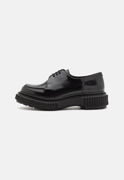Schwarze Lacklederschuhe mit rundem Zeh, dickem strukturiertem Gummisohle und Schnürung mit drei Ösen. Glatte Oberfläche mit minimaler Detailgestaltung.