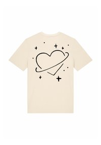 T-shirt beige présentant un graphique de cœur noir entouré d'étoiles et d'un anneau, manches courtes, col rond, en coton doux.