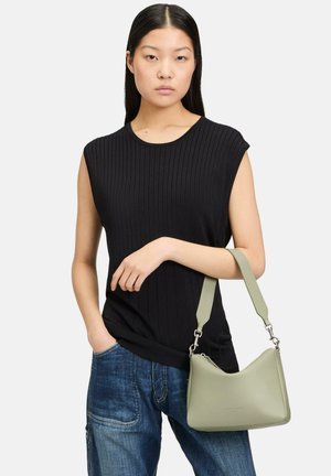 Schwarzes, geripptes, ärmelloses Oberteil mit rundem Ausschnitt, kombiniert mit blauen Jeans. Hält eine hellgrüne Lederhandtasche mit Schultergurt.