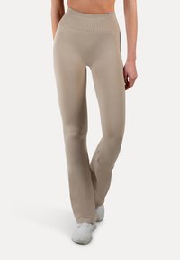 Beige sportlegging met een hoge, geribbelde tailleband en een gladde, rekbare stof. Ontworpen met een uitlopende pijpopening.