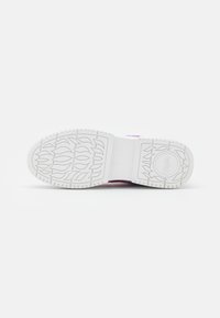 Sola branca de sapato com padrões de pegadas em forma de chama e detalhe de logótipo circular sobre um fundo branco liso.