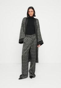 Must mustriga kimono laia varrukaga, kantud musta kõrge kaelusega pluusi ja hallide mustriga pükstega. Kangas on sile ja geomeetrilise mustriga.