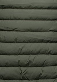 Donkergroene puffer jas met horizontale gestikte secties, een gladde textuur en een lichtgewicht, geïsoleerd ontwerp.