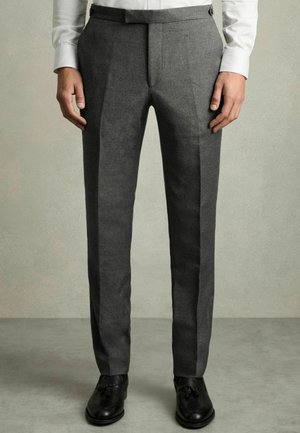 Gray tailored trousers with a smooth texture, feature a flat front, pressed creases, and a classic fit, paired with black shoes.
