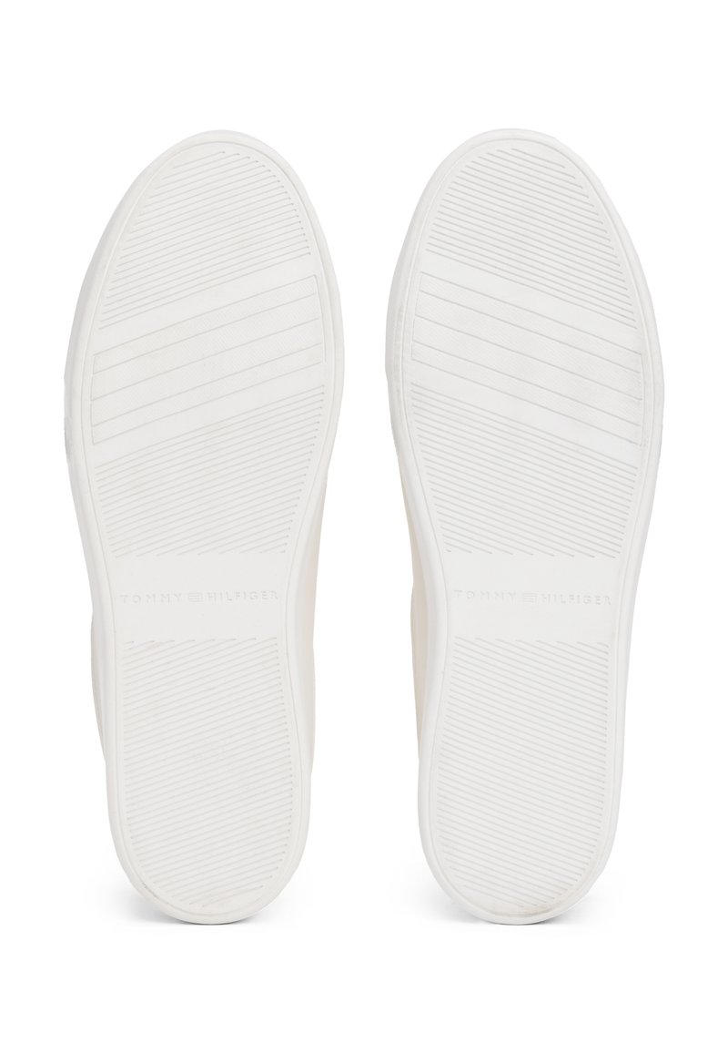 Suole di sneaker bianche in gomma con scanalature orizzontali e verticali per una migliore aderenza. "TOMMY HILFIGER" impresso nella zona del tallone.