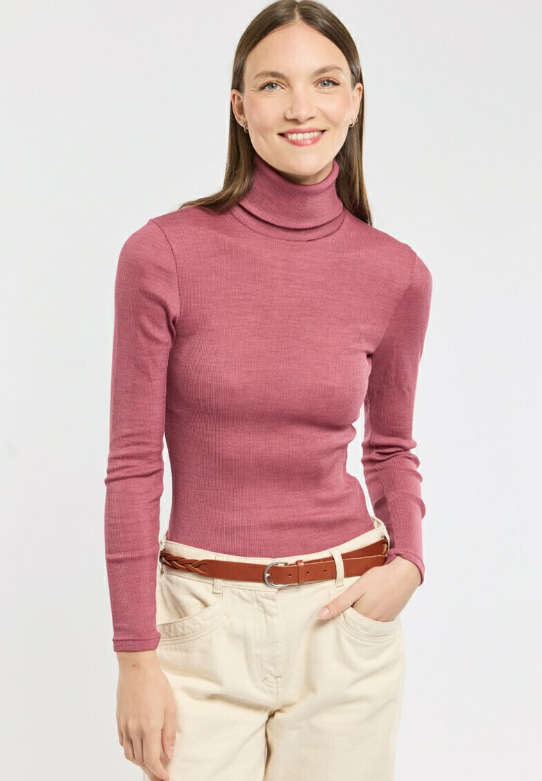 Pull côtelé ajusté en rose, avec col roulé et manches longues, agrémenté d'une ceinture marron et d'un pantalon crème.