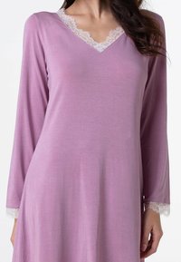 Camicia da notte lilla con maniche lunghe, scollatura a V con decorazione in pizzo e dettagli in pizzo sui polsini, caratterizzata da una texture morbida e liscia e un design fluido.