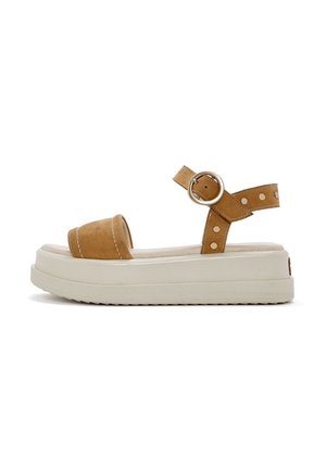 Infradito in suede marrone con plateau, punta arrotondata, cinturino alla caviglia regolabile e decorazioni a pois sul cinturino. Suola in gomma bianca.
