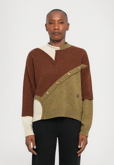Pull en tricot arborant un design en blocs de couleurs dans des tons de marron, vert et crème, avec un col montant, un ourlet asymétrique et des accents de boutons en bois.