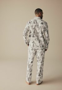 Herren-Pyjama-Set aus weißem Stoff mit schwarzem und grauem Print von Wald und Wildtieren. Langärmeliges Oberteil und lässige Hose. Weicher Stoff.