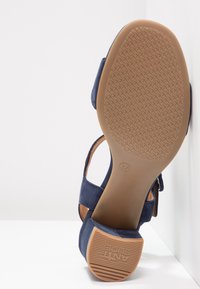Sandale à talon haut en daim bleu marine avec une semelle en caoutchouc texturé, dotée de brides de cheville et d'un bout arrondi. Taille 37 marquée sur la semelle.