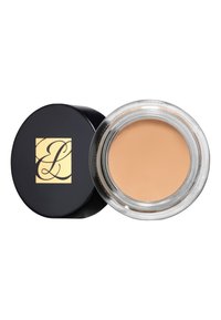 Creamy foundation in a clear glass jar; black lid features a gold logo. Light beige color with a smooth texture.