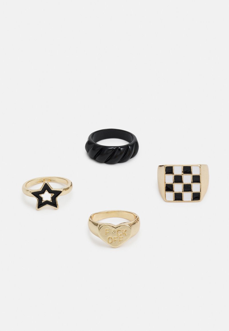 Quatro anéis: uma banda torcida preta, uma estrela dourada com esmalte preto, um coração dourado inscrito "F**K OFF" e um anel dourado com padrão de xadrez.