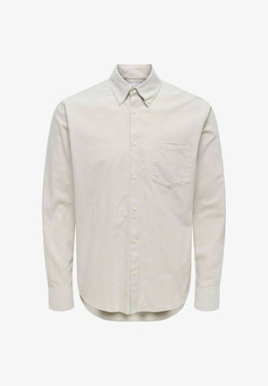 Chemise boutonnée à manches longues de couleur beige clair, fabriquée en tissu doux. Elle présente un col classique, une poche avant et un ourlet arrondi. Coupe standard.