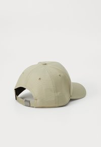Khaki kasket med en afrundet krone, syede paneler og en buet skygge. Har en justerbar rem bagpå med en metalspænde.
