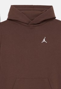 Felpa marrone in morbido tessuto, con tasca a canguro e logo Jumpman bianco sul petto. Il cappuccio ha un design semplice senza decorazioni.