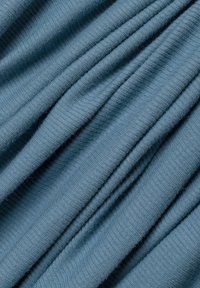 Blauwe ribstof met plooien die diagonale lijnen en zachte schaduwen creëren, waardoor de textuur en het brei-detail worden benadrukt.