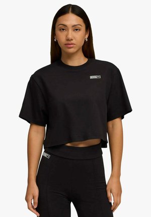 T-shirt corta nera in cotone, con maniche corte, scollo rotondo e una piccola toppa con logo sul petto.