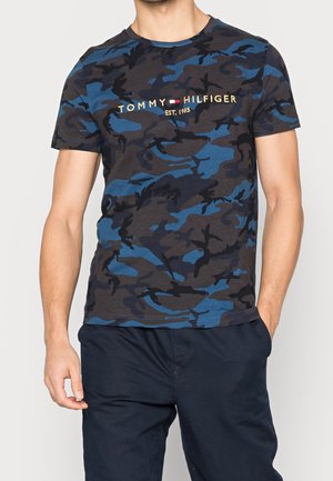 Blaues T-Shirt aus Baumwolle mit Camouflage-Muster und kurzen Ärmeln, mit "TOMMY HILFIGER EST. 1985" in Gold auf der Brust bestickt.