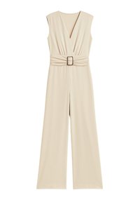 Tuta beige con scollatura a V profonda, senza maniche, vita arricciata e pantaloni a gamba larga. Presenta una fibbia quadrata decorativa in vita.