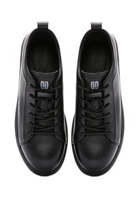 Sneaker in pelle nera con una texture liscia, punta rotonda, design con lacci e accento del logo sulla linguetta. Suola in gomma a profilo basso.