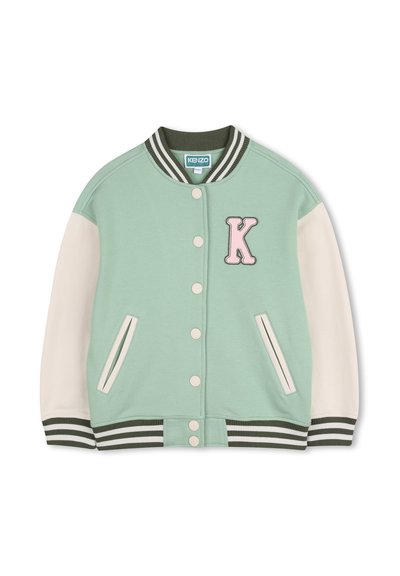Veste universitaire vert menthe avec manches blanches, col et poignets côtelés. Présente un grand patch "K" rose et des boutons-pression à l'avant.