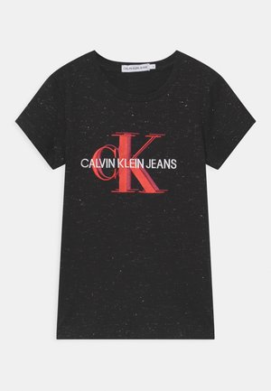 Camiseta de algodón negra con mangas cortas, que presenta un logo prominente en rojo y blanco de "CALVIN KLEIN JEANS" en el pecho.