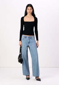 Black ribbed long-sleeve top, square neckline, paired with light blue wide-leg jeans, black pointed-toe heels, and a black handbag.