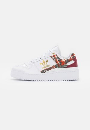 Biały sneaker Adidas z grubą podeszwą, złotym logo i wzorem w czerwono-czarno-zieloną kratę na boku i panelu pięty.