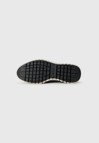 Black rubber shoe sole with a thick, textured tread pattern and a beige edge trim. Features branding on the central part of the sole.