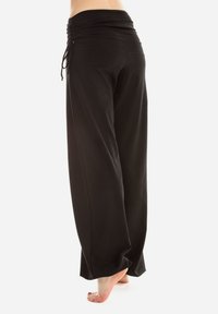 Black wide-leg pants with a high, gathered waistband and drawstring feature. The fabric appears soft and lightweight.