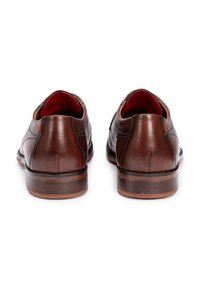 Chaussures en cuir marron avec une finition lisse, bout arrondi, détails de piqûre subtils, talon bas et accent rouge à l'arrière.