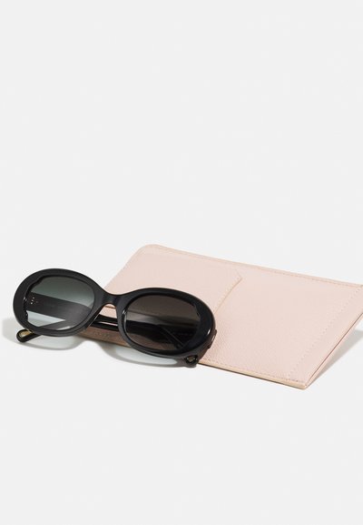 Zwarte ovale zonnebrillen met een gradient lens, geplaatst op een lichtroze textuur leren etui met een insteekvak.